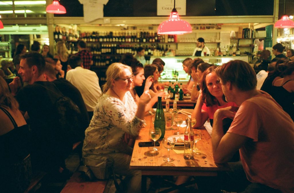 A bustling restaurant scene with people enjoying drinks and conversations on a lively night.