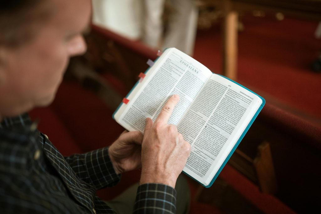 An individual reads a Bible in a church pew, focusing on Ephesians.